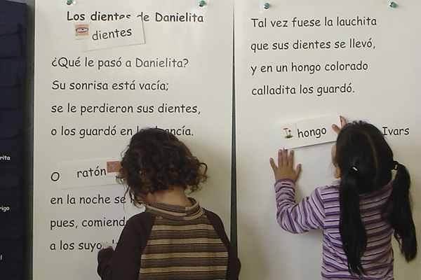 Segmentación silábica La imagen muestra a dos niñas pegando palabras en un cuento en el pizarrón