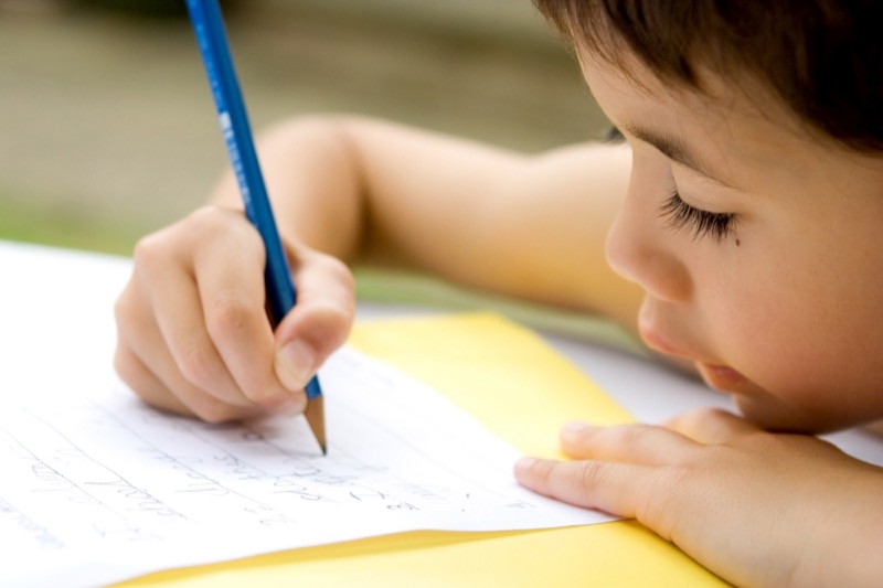 Palabras La imagen muestra a un niño escribiendo letras en un cuaderno