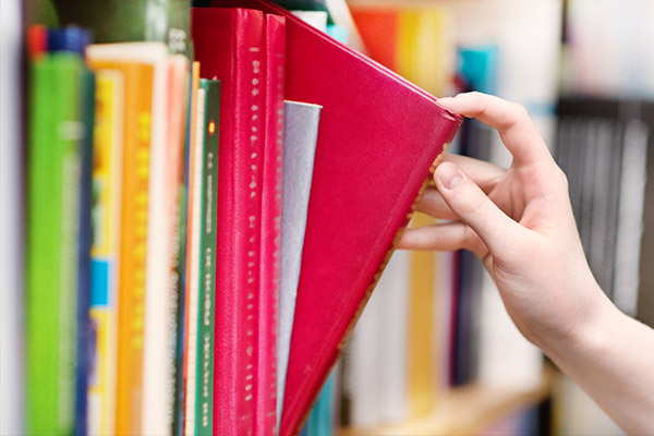 Epopeyas La imagen muestra un estante de libros y una mano escogiendo uno de los textos
