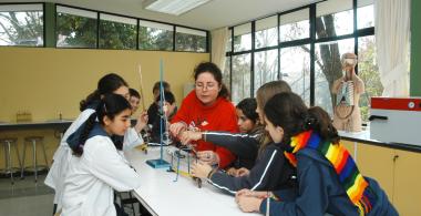 Estudiantes con docentes realizando experimento en laboratorio de ciencias