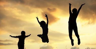La imagen muestra a tres personas que saltan, manifestando optimismo