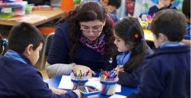 Fotografía de profesora apoyando a sus estudiantes con una investigación. 
