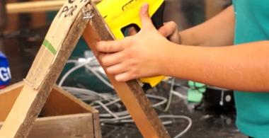 la imagen muestra un estudiante utilizando materiales reciclados para un proyecto
