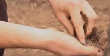 La imagen muestra unas manos con tierra en posición de revisión de la misma 