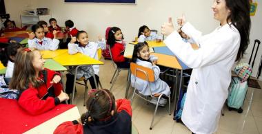 Profesora habla a sus estudiantes sentados en el aula