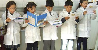 La imagen muestra un grupo de estudiantes de pie leyendo al curso un fragmento de un libro de trabajo