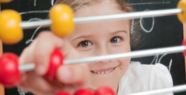 La imagen muestra a una niña contando con pelotitas de color rojo y amarillo